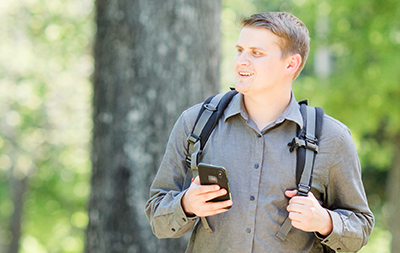 Male student with backpack on standing outside